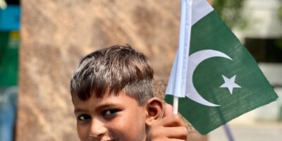 a young boy smiling while holding a flag