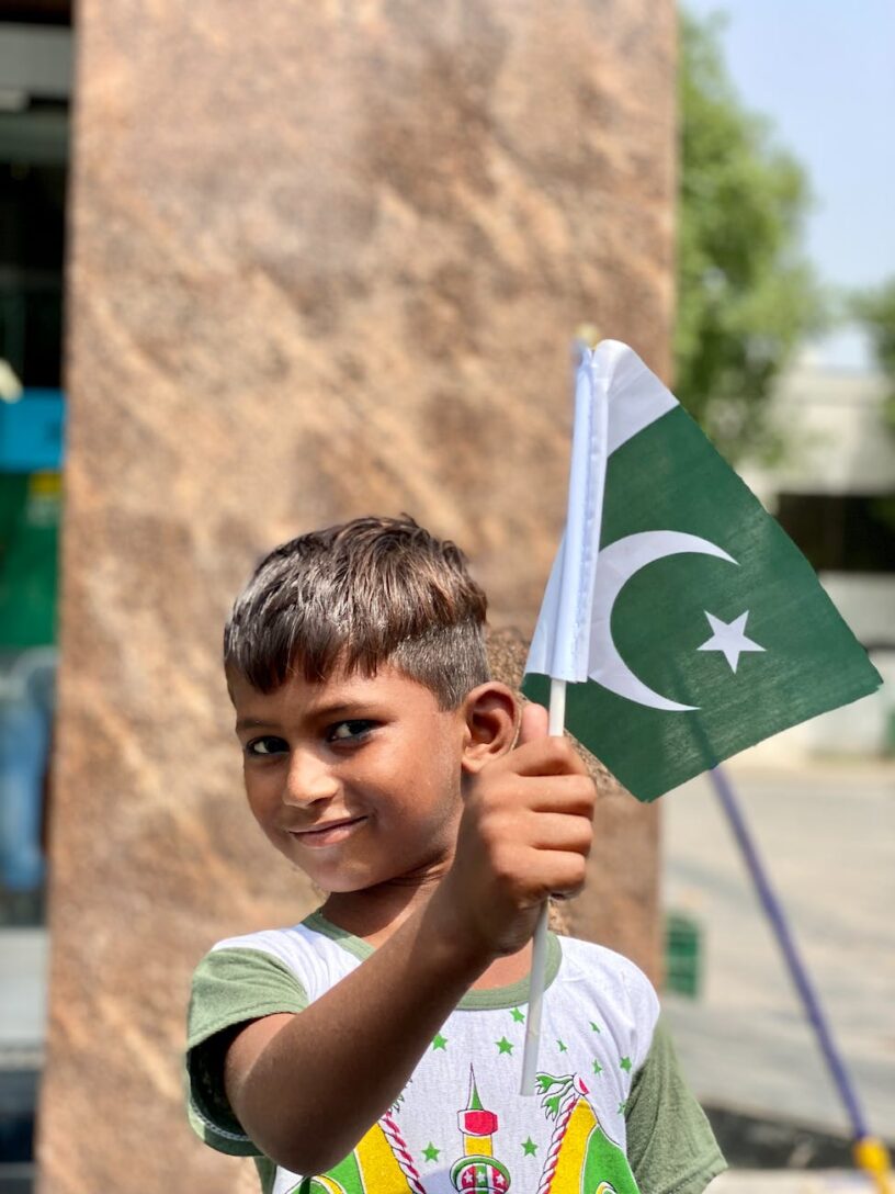 a young boy smiling while holding a flag